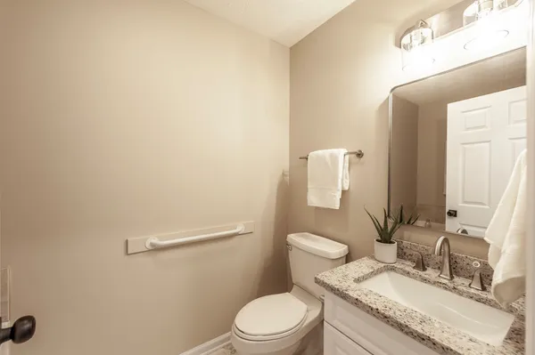 a bathroom with a granite countertop sink mirror vanity and toilet