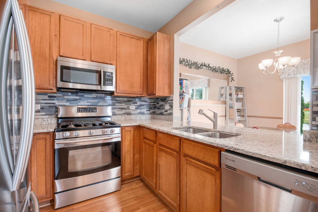 1070 Clover Drive Minooka, IL 60447 - Photo 4 of 15 a kitchen with granite countertop a stove sink and microwave