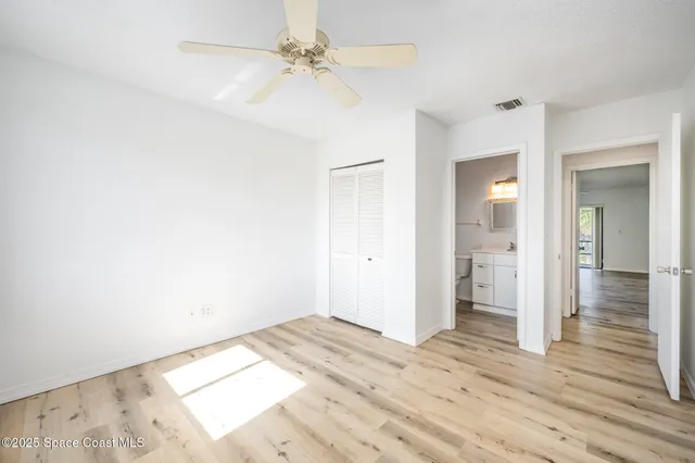 a view of a room with wooden floor and a ceiling fan