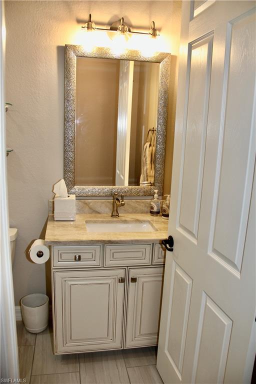 9449 Rialto Drive Naples, FL 34113 - Photo 38 of 44 a bathroom with a granite countertop toilet a sink and a mirror