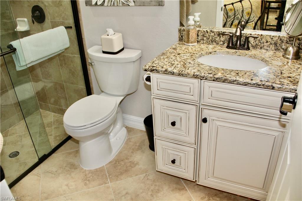 9449 Rialto Drive Naples, FL 34113 - Photo 42 of 44 a bathroom with a granite countertop toilet sink and mirror