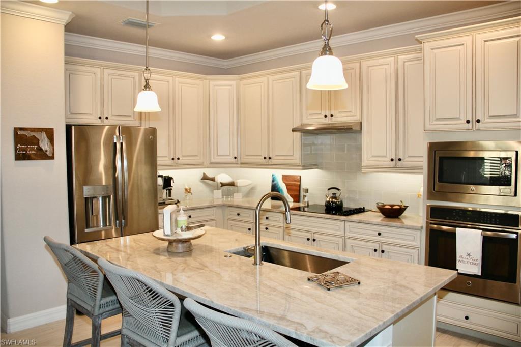 9449 Rialto Drive Naples, FL 34113 - Photo 9 of 44 a kitchen with stainless steel appliances granite countertop a sink refrigerator and cabinets