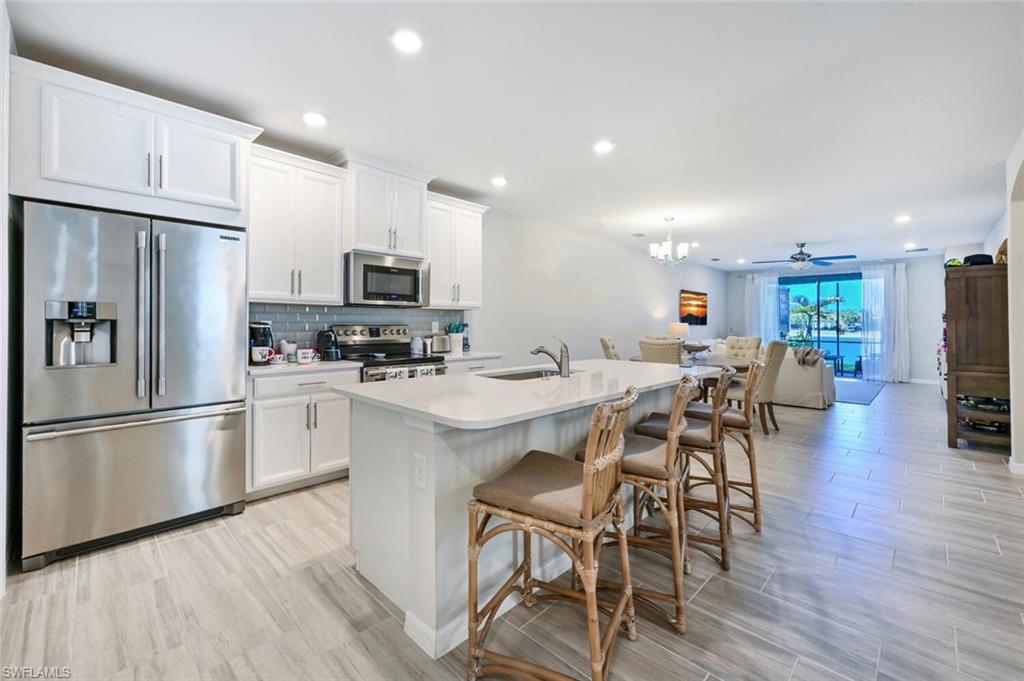 14680 Edgewater Circle Naples, FL 34114 - Photo 11 of 21 a kitchen with stainless steel appliances a refrigerator stove microwave and cabinets with wooden floor