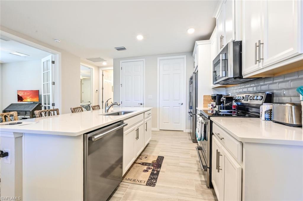 14680 Edgewater Circle Naples, FL 34114 - Photo 13 of 21 a kitchen with stainless steel appliances granite countertop a sink and cabinets