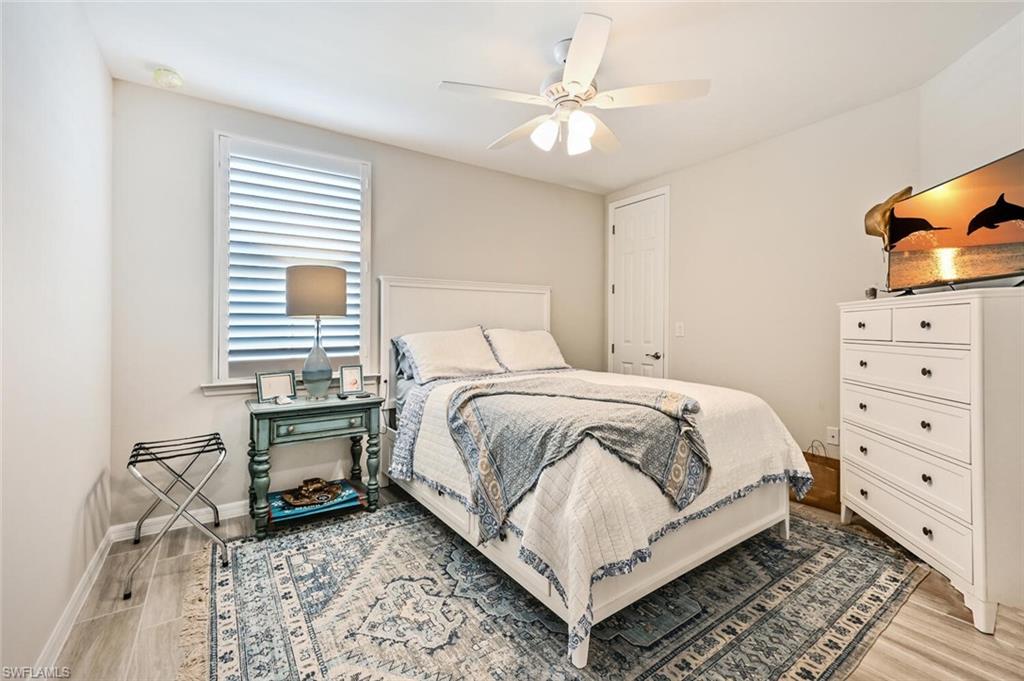 14680 Edgewater Circle Naples, FL 34114 - Photo 19 of 21 a bedroom with a bed a chair and dresser with wooden floor
