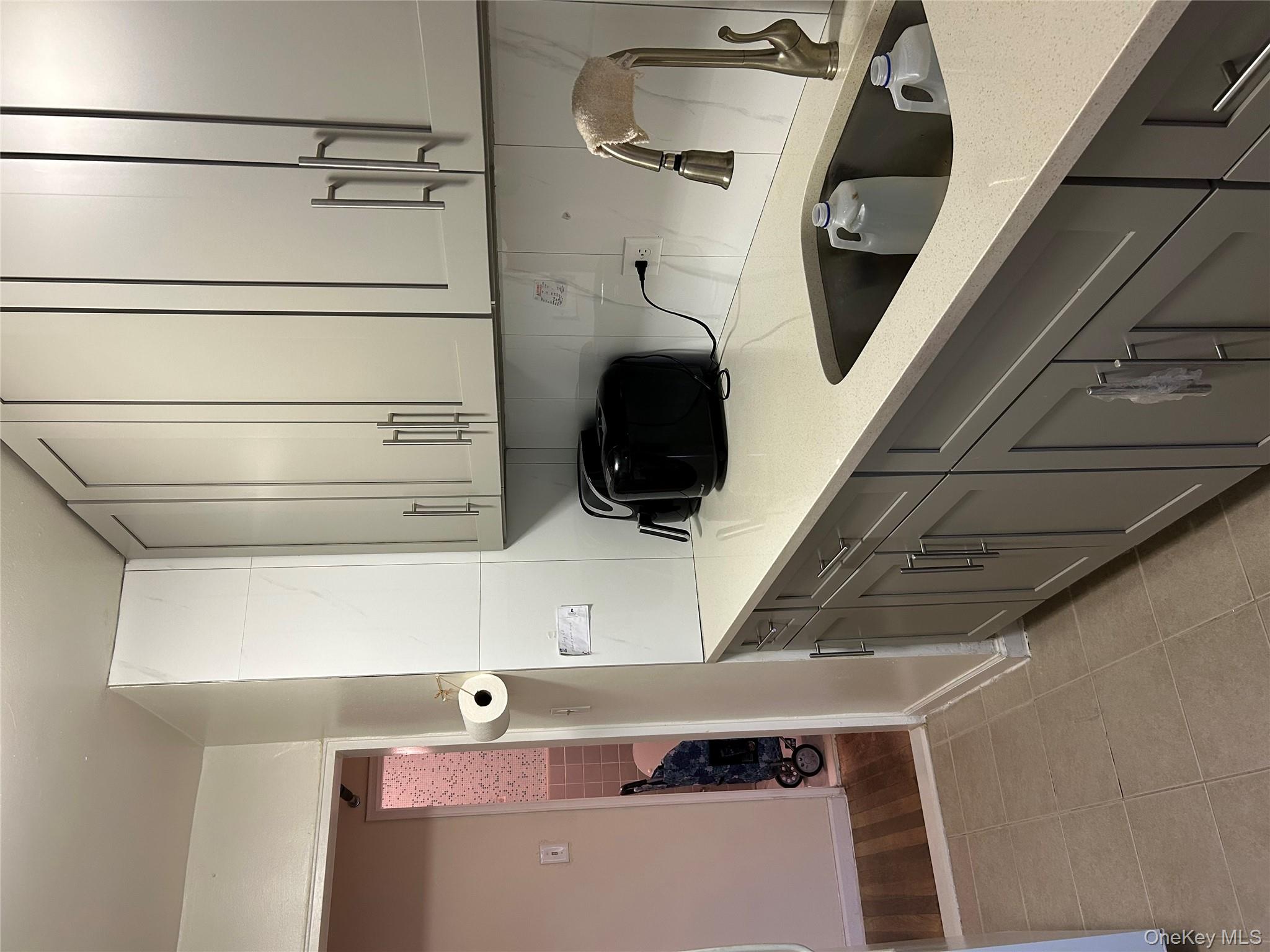 99-05 59th Avenue, Unit 6B Queens, NY 11368 - Photo 12 of 16 Kitchen featuring gray cabinets, light stone countertops, light tile patterned floors, and tasteful backsplash