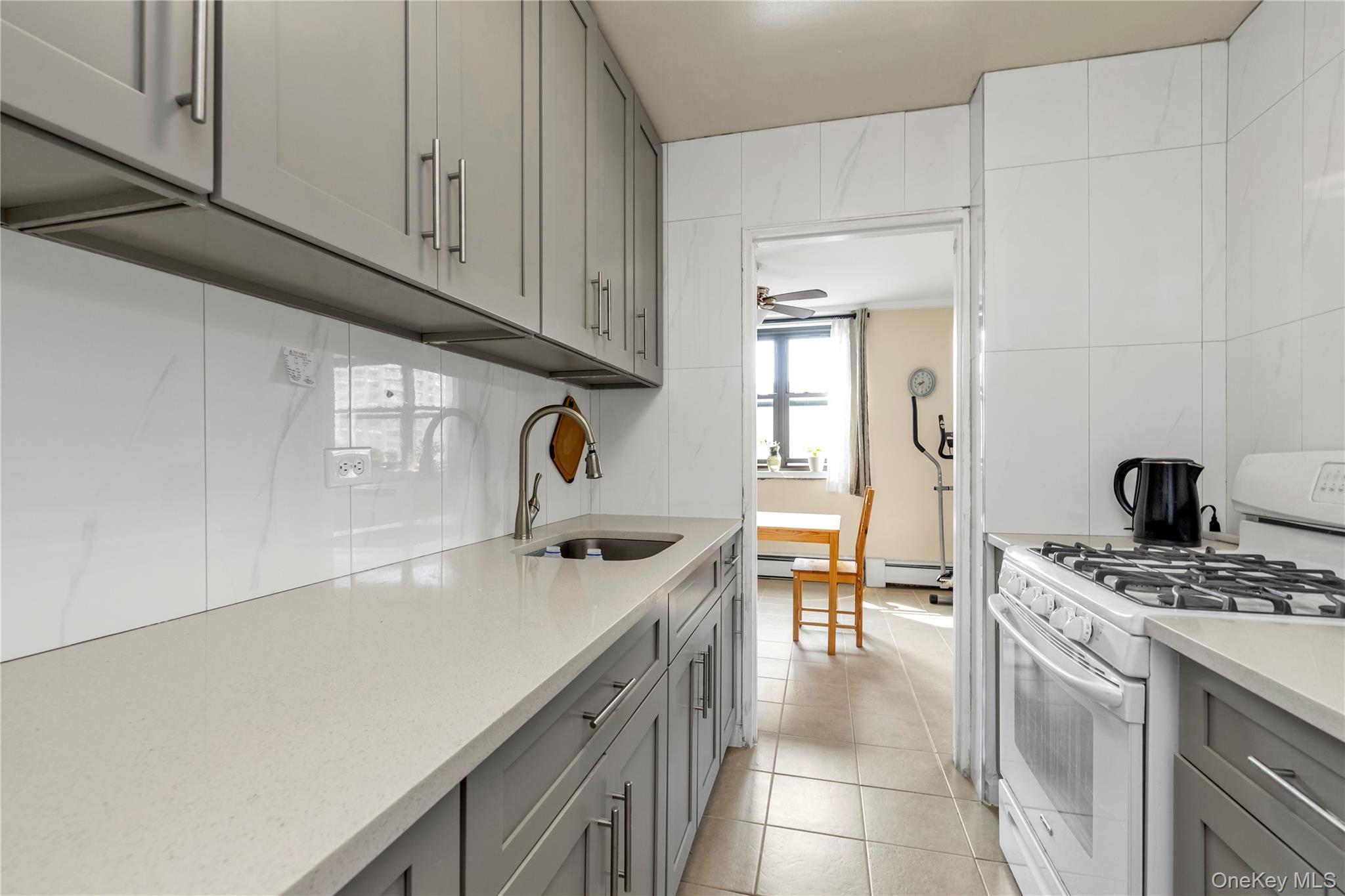 99-05 59th Avenue, Unit 6B Queens, NY 11368 - Photo 13 of 16 Kitchen featuring gray cabinetry, gas range gas stove, light countertops, and light tile patterned floors