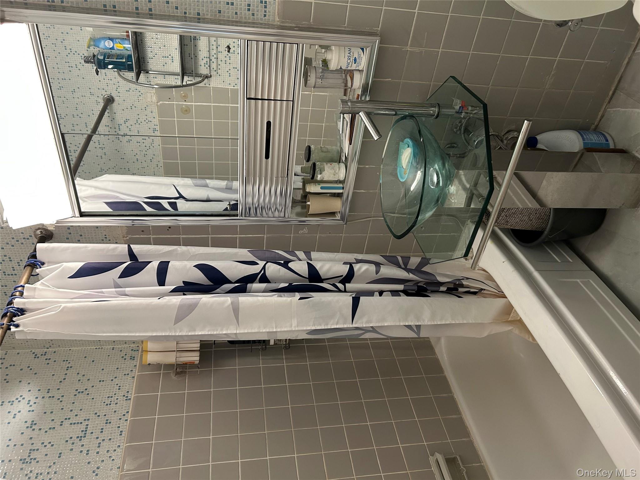 99-05 59th Avenue, Unit 6B Queens, NY 11368 - Photo 14 of 16 Full bathroom featuring tile walls, shower / bath combination with curtain, decorative backsplash, and tile patterned flooring