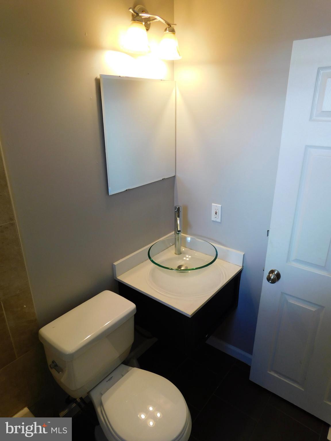 7009 Fieldcrest Road Baltimore, MD 21215 - Photo 25 of 46 a bathroom with a toilet a sink and mirror