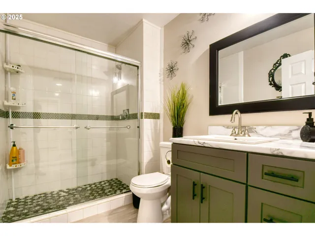 a bathroom with a granite countertop sink toilet a mirror and shower