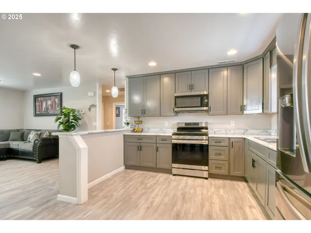 a kitchen with stainless steel appliances kitchen island granite countertop a stove a sink a refrigerator and a microwave