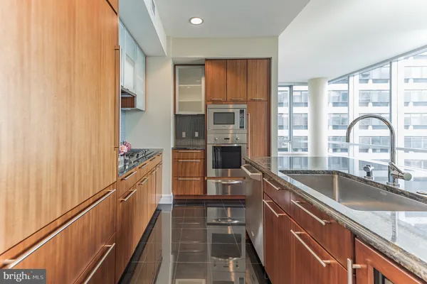 a kitchen with kitchen island granite countertop a sink stove and cabinets