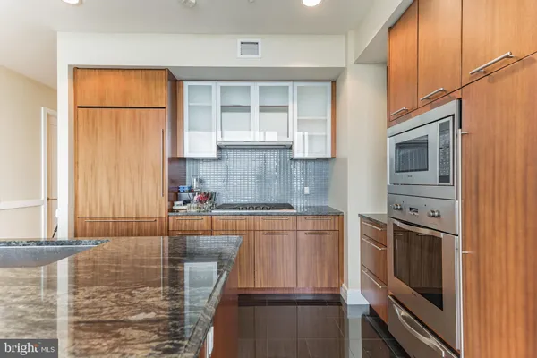 a kitchen with stainless steel appliances granite countertop a refrigerator a stove and a sink with wooden floor