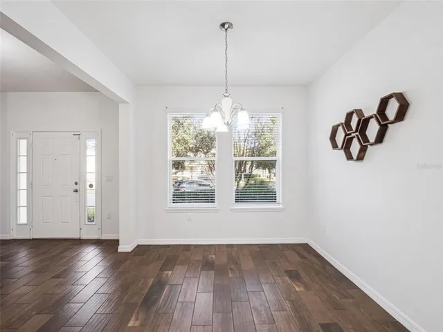 a view of an empty room with wooden floor and windows
