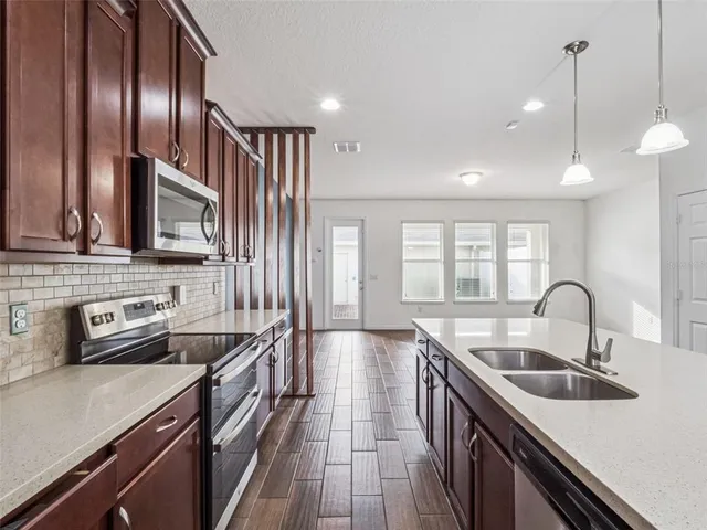 a kitchen with stainless steel appliances a sink a stove and a wooden floors