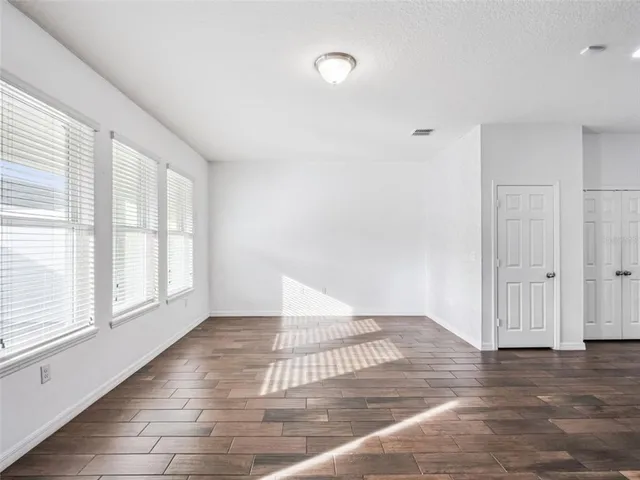 a view of an empty room with wooden floor and a window