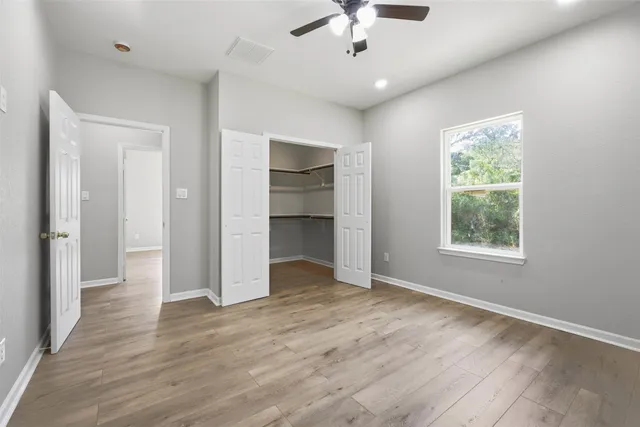 an empty room with wooden floor chandelier and windows