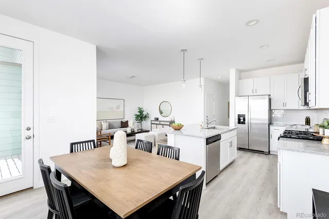 a open dining room with stainless steel appliances kitchen island a table chairs and a refrigerator
