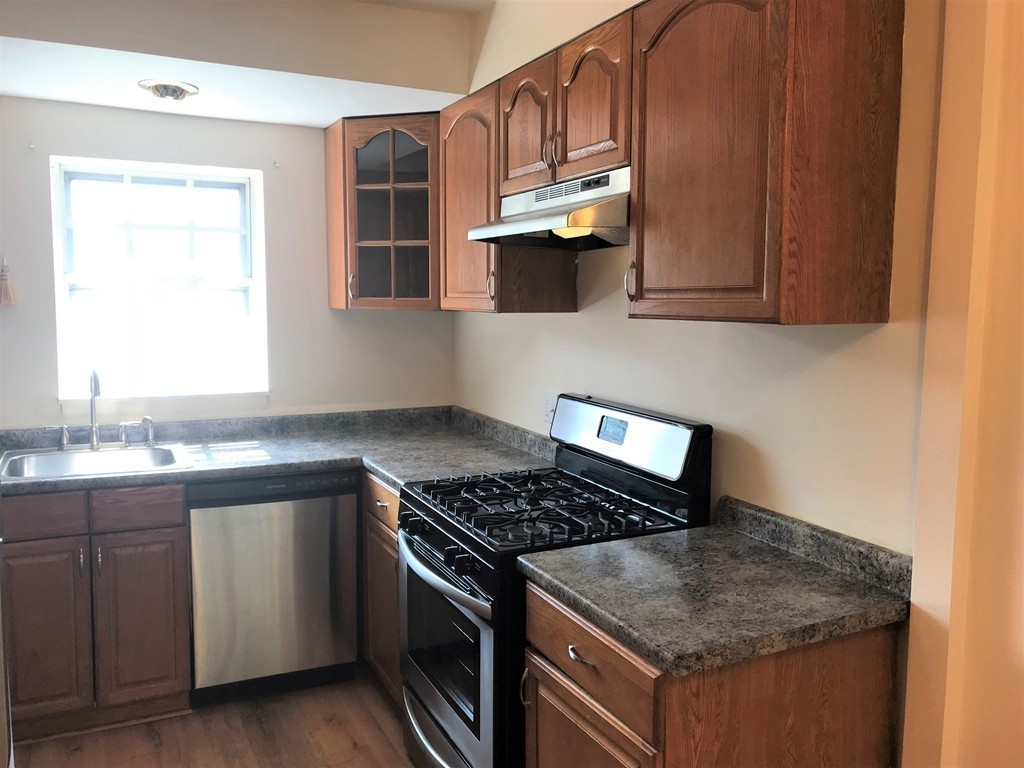 157 Lake Shore Road, Unit 4 Boston, MA 02135 - Photo 3 of 11 a kitchen with stainless steel appliances granite countertop a sink stove and cabinets