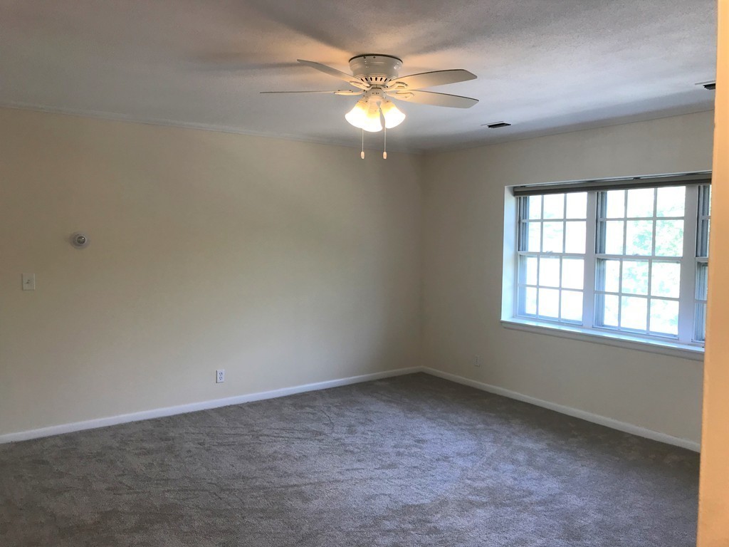 157 Lake Shore Road, Unit 4 Boston, MA 02135 - Photo 4 of 11 an empty room with chandelier fan and windows