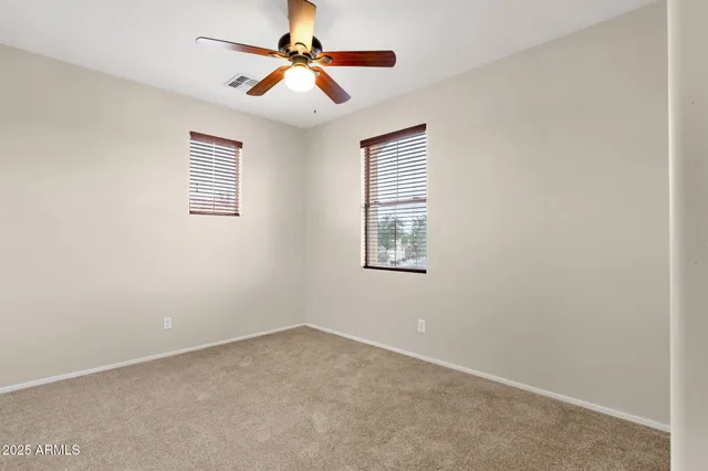 an empty room with windows and fan