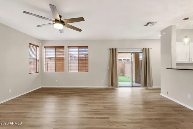 a view of an empty room with window and wooden floor