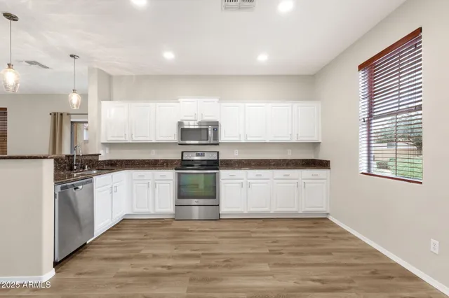 a kitchen with granite countertop white cabinets and stainless steel appliances