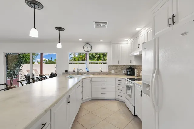 a large white kitchen with a sink window and stainless steel appliances
