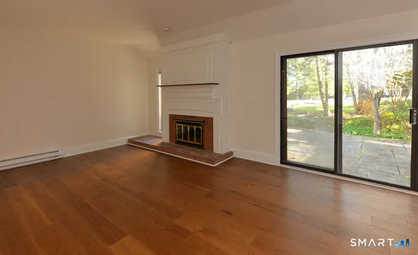 an empty room with wooden floor fireplace and windows