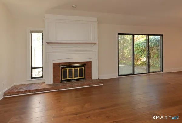a view of an empty room with window and wooden floor
