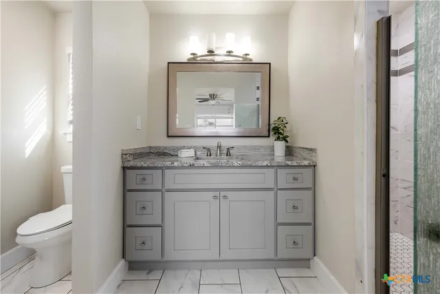 a bathroom with a granite countertop toilet sink and mirror