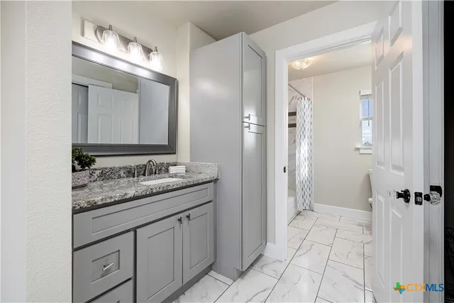 a bathroom with a granite countertop sink and a mirror