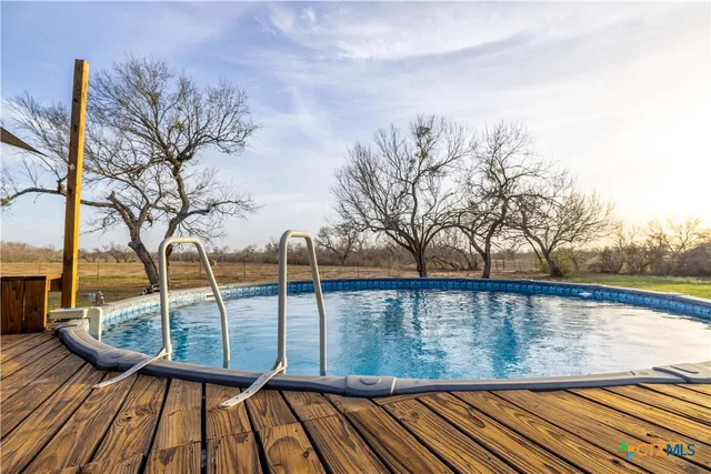 a view of swimming pool with trees and wooden fence