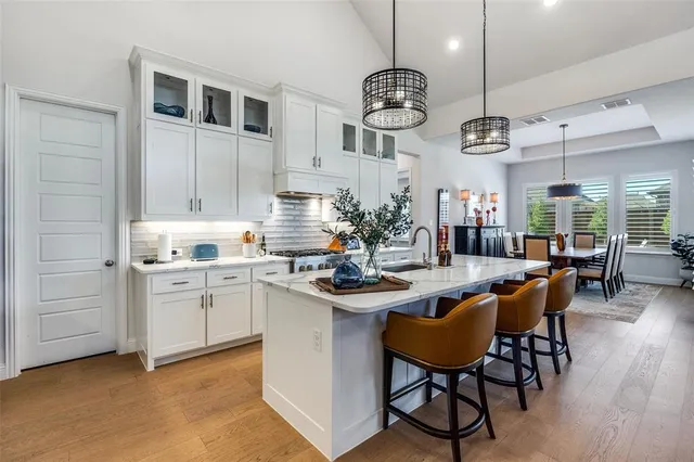 a kitchen with stainless steel appliances kitchen island granite countertop a table chairs sink and cabinets