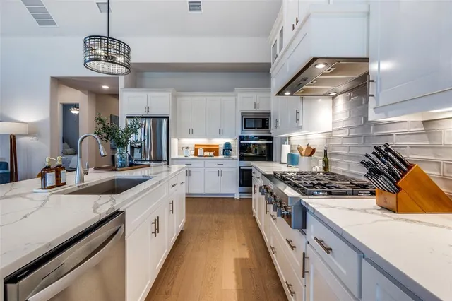 a kitchen with stainless steel appliances granite countertop a sink a stove and a wooden floors