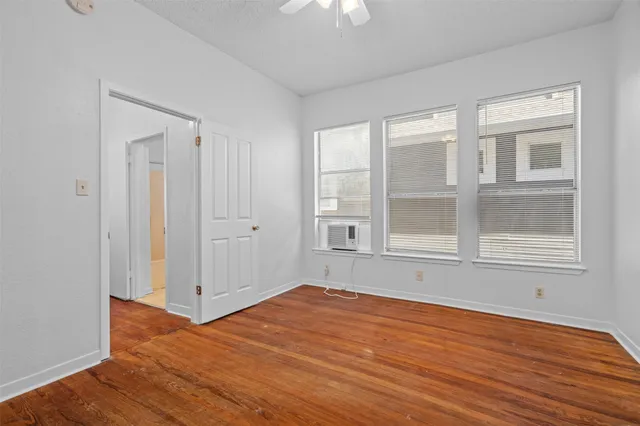 a view of empty room with wooden floor and fan