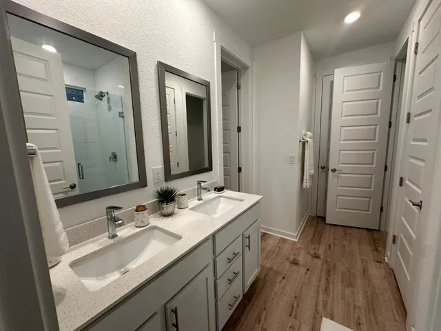 a bathroom with a double vanity sink a mirror and a shower