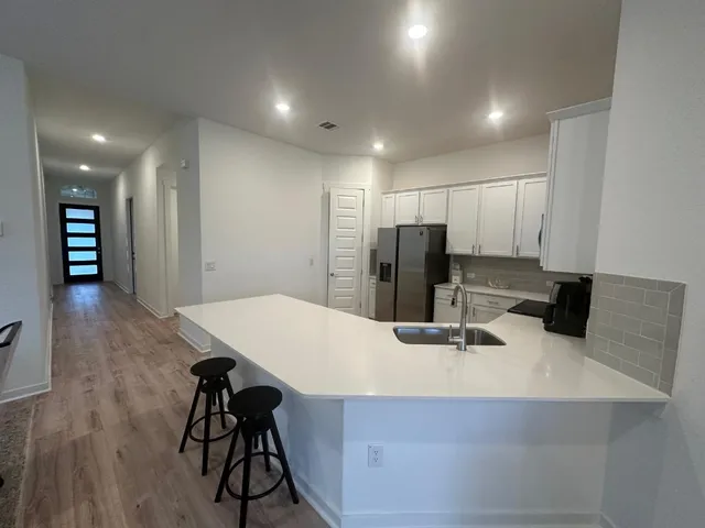 a kitchen with stainless steel appliances kitchen island granite countertop a refrigerator a stove and a sink with wooden floor