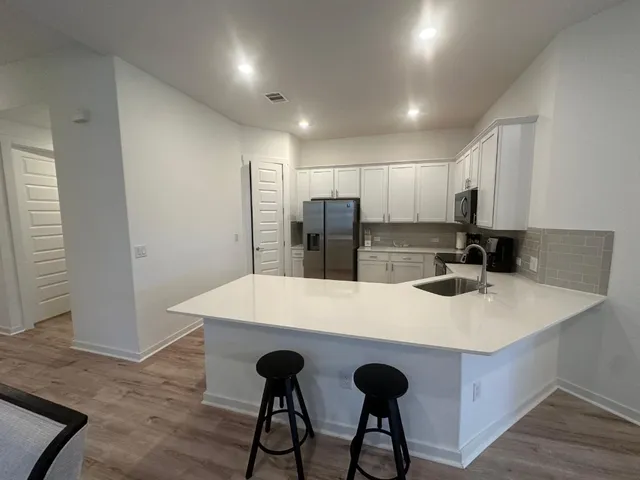 a large kitchen with sink a refrigerator and chairs
