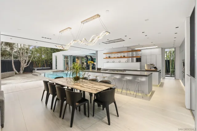 a dining hall with stainless steel appliances kitchen island a table and chairs in it