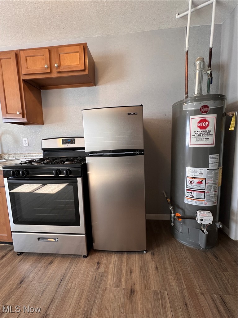 1724 Youngstown Kingsville Road, Unit 4 Vienna, OH 44473 - Photo 7 of 11 Kitchen with water heater, range, freestanding refrigerator, brown cabinetry, and dark wood finished floors