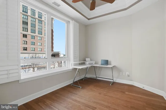 a view of an empty room with a window and wooden floor