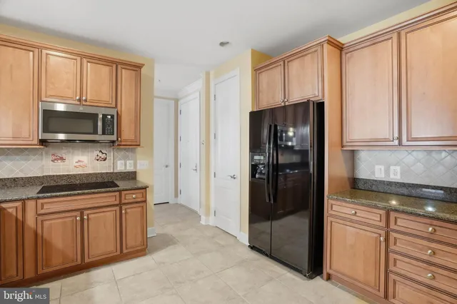 a kitchen with stainless steel appliances granite countertop a refrigerator and a stove top oven