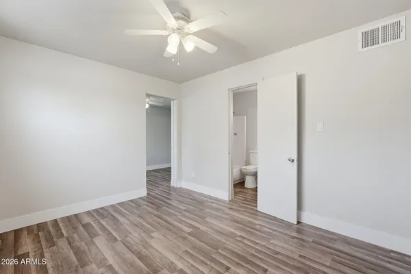 an empty room with wooden floor and ceiling fan