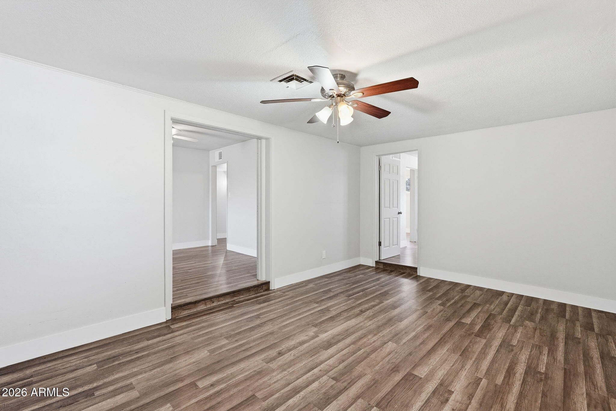 2206 West Rancho Drive Phoenix, AZ 85015 - Photo 18 of 29 a view of an empty room with wooden floor and a ceiling fan