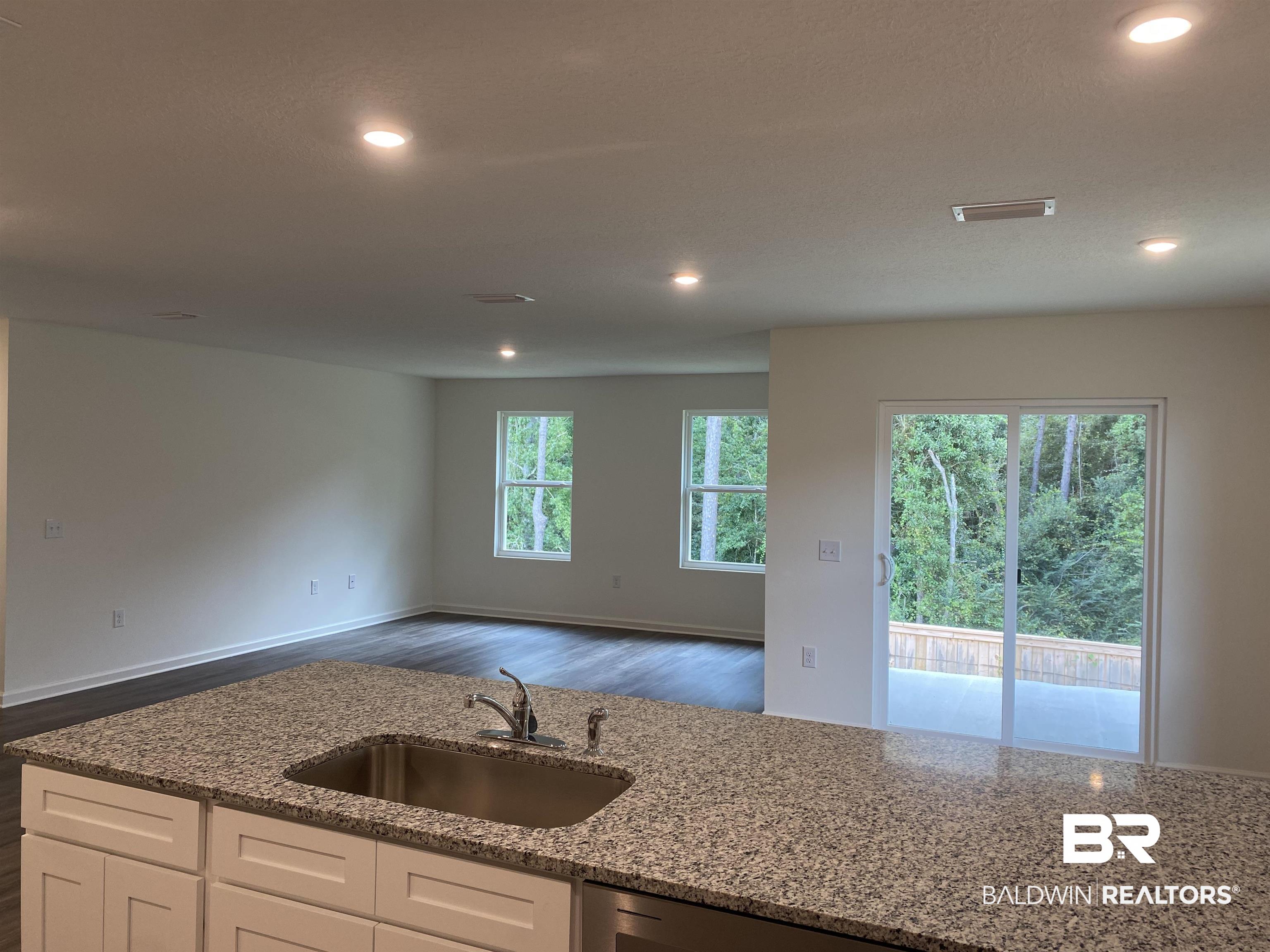21676 Yosemite Boulevard Fairhope, AL 36532 - Photo 4 of 19 Kitchen with white cabinetry, light stone countertops, dark wood-type flooring, and sink