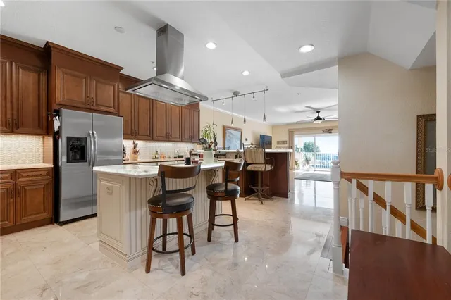 a kitchen with stainless steel appliances kitchen island granite countertop a table chairs and a refrigerator