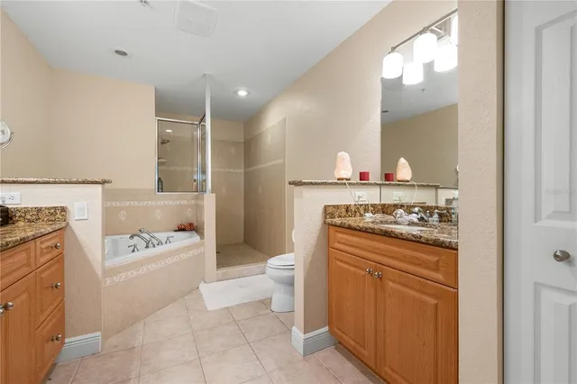a bathroom with a granite countertop sink toilet mirror vanity and bathtub