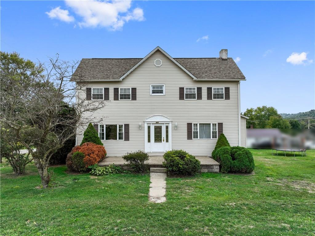 a front view of a house with a yard and trees