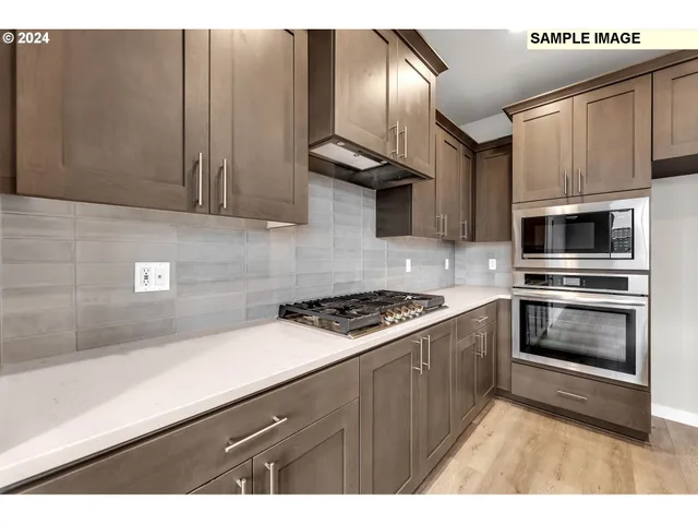 a kitchen with cabinets stainless steel appliances and wooden floor